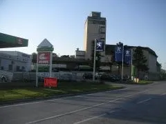 Eine leere Straße führt zu einem Gebäude mit einem hohen Turm und mehreren Fahnen davor.