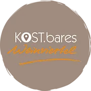 Ein braunes kreisförmiges Logo mit dem Text 'KOST.bares' und 'Weinviertel' in weißen und orangefarbenen Schriften.