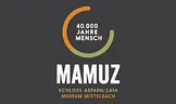 Das Mamuz-Logo zeigt einen schwarzen Hintergrund mit weißem Text, der 'Mamuz' lautet. Darunter befindet sich ein kleinerer Text, der 'Schloss Asparn/Zaya Museum Mistelbach' lautet. Über dem 'Mamuz'-Text befindet sich eine kreisförmige Grafik mit dem Text '40.000 Jahre Mensch'.