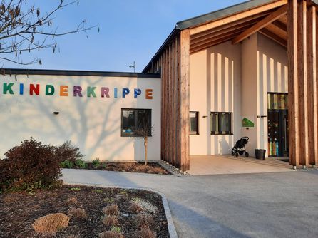 Ein Gebäude namens 'Derkripple' mit bunten Buchstaben, einem Holzpfosten, einem Kinderwagen und einem Topf.
