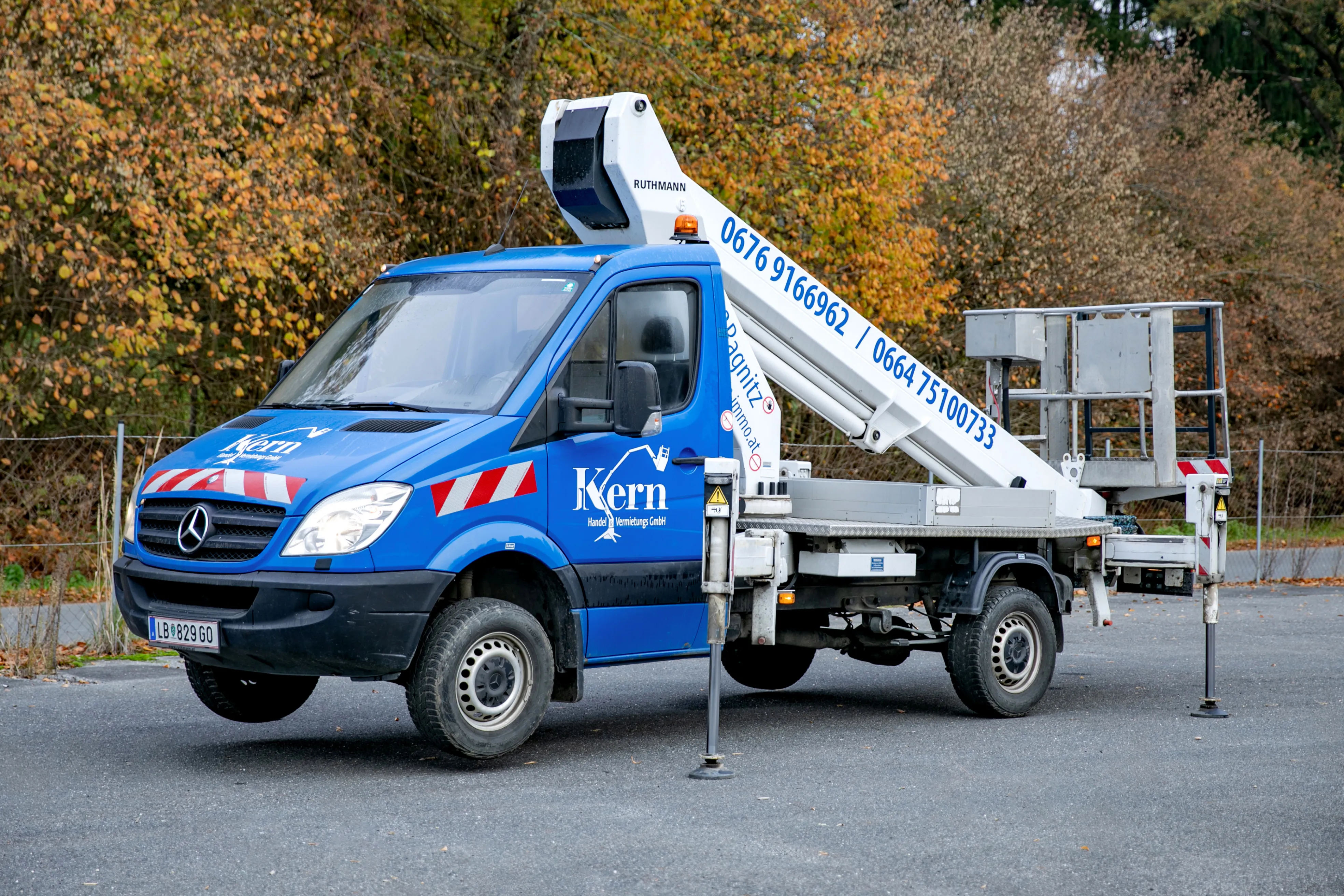 Ein blauer Kern-Lkw mit einem Kran auf der Rückseite steht auf einem Parkplatz.