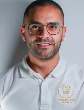 Ein lächelnder Mann mit Brille und Bart, der ein weißes Poloshirt mit einem Logo auf der linken Seite seiner Brust trägt.